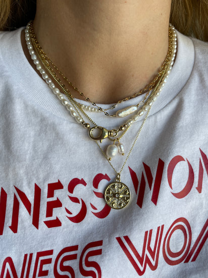 stack of gold and pearl necklaces on a t-shirt